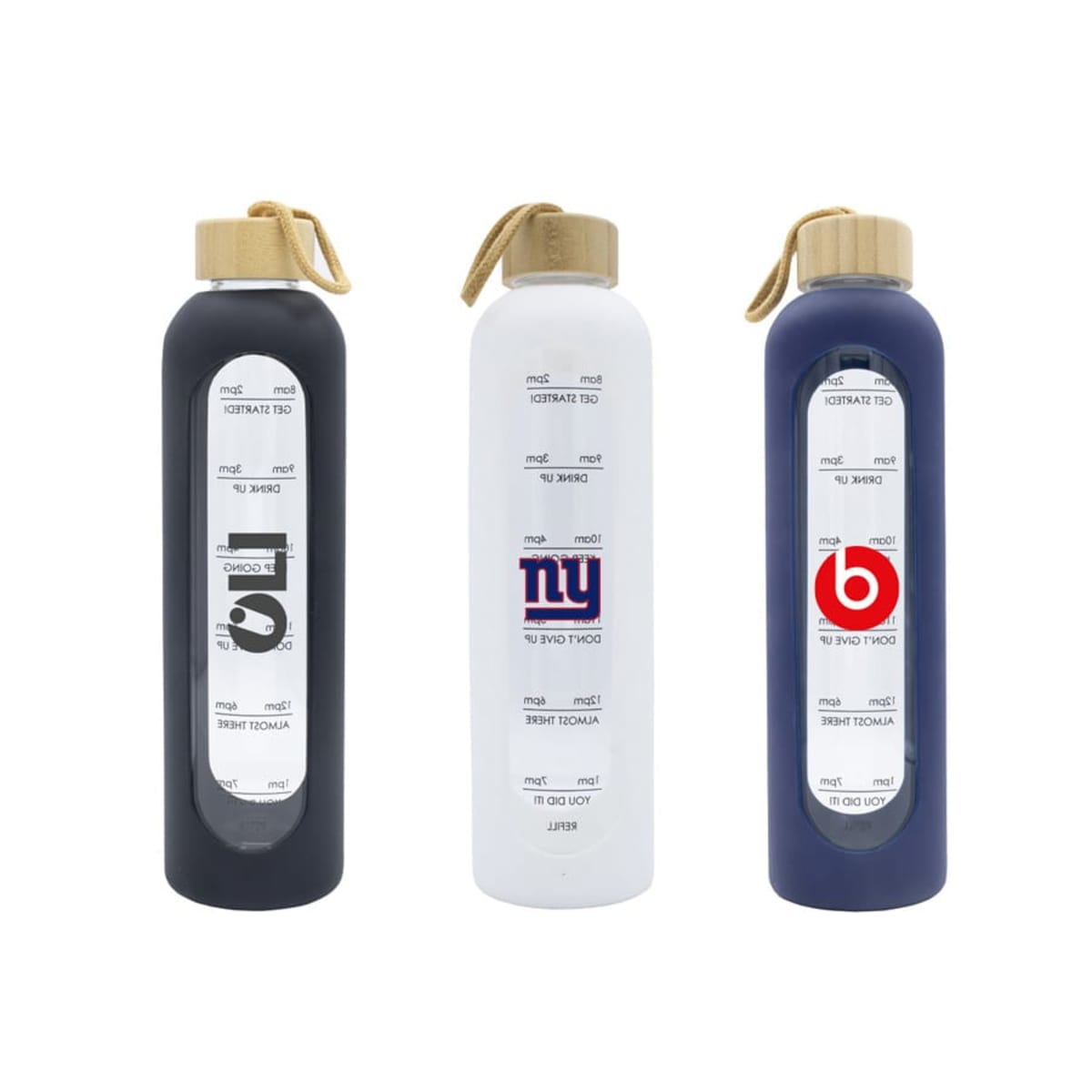 Three reusable water bottles with wooden caps and measurement markings are displayed. One bottle is black with a G logo, the middle bottle is white with an N logo, and the last bottle is dark blue with a B logo.
