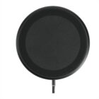 A round, black wireless charging pad with a smooth surface is centered on a white background. A small charging cable is attached at the bottom of the pad.