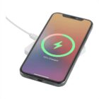 A smartphone resting on a wireless charging pad. The screen displays a charging symbol with a circle, indicating it is 75% charged. The background is a gradient of warm colors. The pad is connected to a power cable.