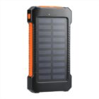 A portable solar power bank with a black and orange rugged design. The front panel features solar cells and LED indicators for battery status. It appears durable and suitable for outdoor use.