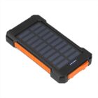 A portable solar power bank with a black and orange design is shown. It features a solar panel on the top and four small LED indicator lights, likely for battery charge status.