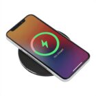 Smartphone on a round, black wireless charging pad with a colorful screen displaying a green charging icon and 75% Charged.