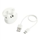 White wireless earphones in an open charging case next to a USB-C to USB-A charging cable against a plain background.