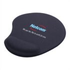 Black ergonomic mouse pad with wrist support. The text Netcom and We put the Net to work for you appears on the surface.