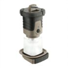 A portable camping lantern with a rugged, black and gray design. It has a textured grip, a button switch, and a hook at the top for hanging. The base is circular, and the lamp emits light through a frosted section in the middle.