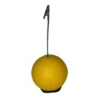A yellow spherical object with a metal rod protruding from the top, featuring holes at the end. The object has a flat black base. The background is white.