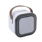 A white portable speaker with a brown handle. It has a square shape with rounded edges, a black frame around the front speaker grille, and control buttons on top.