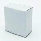 A small, plain white cardboard box is standing upright against a white background. The box has visible edges and a slight shadow on the surface, suggesting a three-dimensional, minimalist appearance.