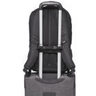 Back of a black backpack attached to the extended handle of a gray rolling suitcase. The backpack is secured with a strap on the suitcase handle, ready for travel. The setup suggests ease and mobility for the traveler.