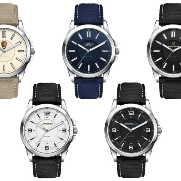 A collection of five wristwatches arranged in a grid. The top left has a beige strap and cream dial, the top center has a blue strap and navy dial, and the rest have black straps with black or white dials. All feature a sleek, minimalist design.