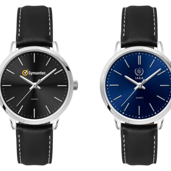 Two wristwatches with black leather bands. The left watch has a black face with the Symantec logo, while the right watch has a blue face with the IAEA logo. Both have silver hour markers and simple designs.