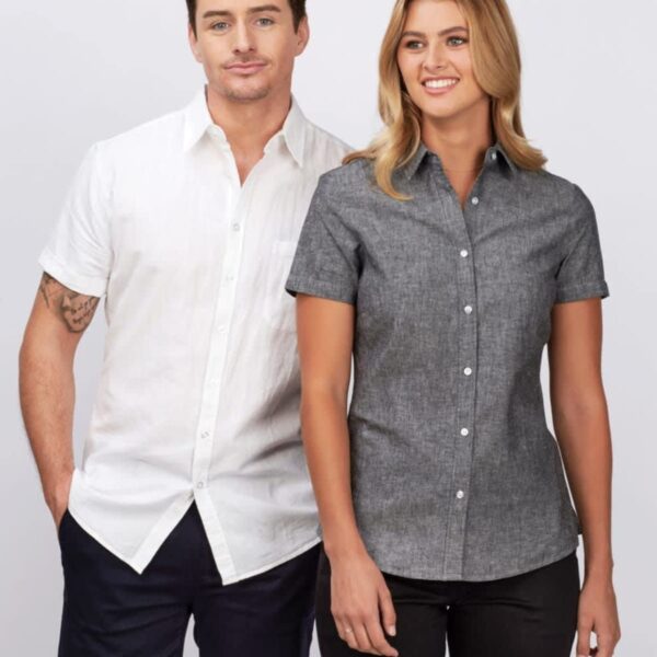 A person wearing a white short-sleeve shirt and dark shorts stands next to another person in a gray short-sleeve button-up shirt and black shorts. Both smile in front of a light gray background.