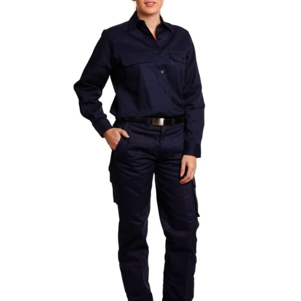 A person stands against a white background, wearing a navy blue uniform with long sleeves and cargo pants. They have one hand in their pocket and are wearing black shoes.