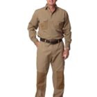 A man in a tan work outfit with pockets on the chest and knees stands smiling. He wears black shoes and a black belt, with his hands relaxed by his sides against a plain white background.