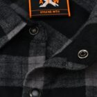 Close-up of a black and gray plaid shirt with metal snap buttons. The label reads A X W, Style No. WT11 with an orange and black design.