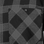 Close-up of a black and gray plaid shirt with a front pocket. The pocket has a button closure and the plaid pattern is composed of intersecting lines forming squares and rectangles.