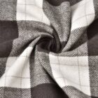 Close-up of a black and white plaid fabric with a swirling pattern at the center, creating a dynamic, twisted effect. The checkered design features large squares with fine lines for added texture.