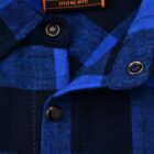 Close-up of a blue and black plaid shirt with metallic snap buttons. A visible orange tag at the collar reads AXM and STYLE NO. WT11.
