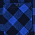 Close-up of a blue and black plaid fabric with a pocket. The pocket has a button closure at the top center. The fabric features a pattern of intersecting lines forming checkered squares.