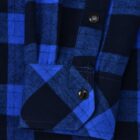 Close-up of a blue and black plaid fabric with a buttoned cuff and sleeve detail. The fabric has a checkered pattern with vibrant blue and dark navy tones.