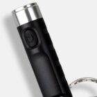 Close-up of a black flashlight keychain with a power button.