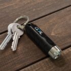 Two silver keys and a black flashlight keychain labeled GOAL on a wooden surface.