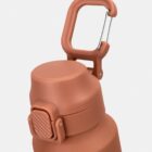 Close-up of a brown water bottle with a flip-top lid and a built-in carrying handle.