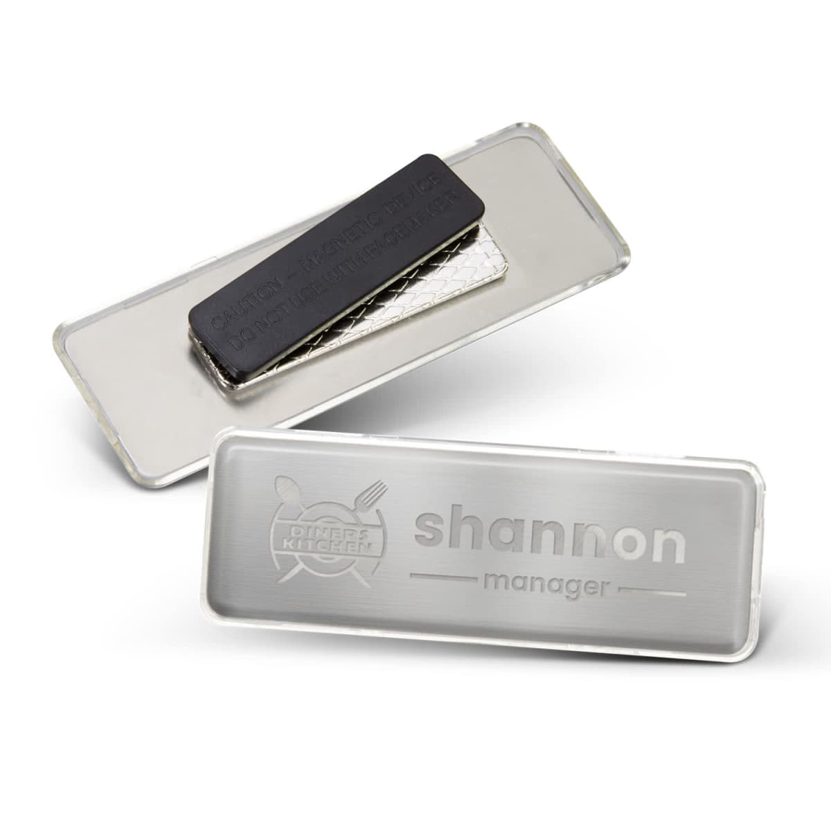 Two metal name badges, one showing the text shannon manager, the other shows the back side.