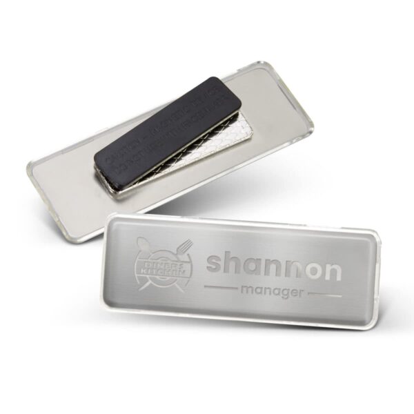 Two rectangular metal name badges, one showing shannon manager, the other showing the back.