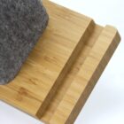 Close-up of a grey felt object on a light wooden platform with a grooved edge.