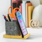 Gray desk organizer with pens, scissors, and a phone; books and decor in the background.