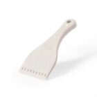 A white plastic scraper with a flat, toothed edge and a hole in the handle.