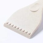 Beige plastic scraper with a flat edge and small teeth along one side, on white background.