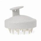 White scalp massager brush with short, pointed bristles and a handle on top.