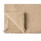 Beige bath towel with one corner folded over on a white background.