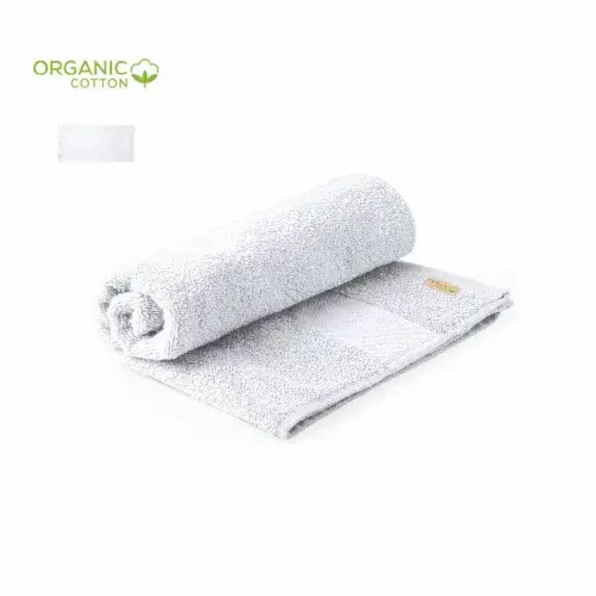 Rolled white organic cotton towel with a label, lying on an unfolded towel.
