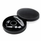 Round black case with wine opener, stopper, pourer, and drip ring inside.