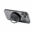 Black smartphone with a circular ring stand attached to the back, propping it up horizontally.