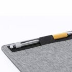 A pen held by an elastic loop on a grey fabric surface.