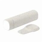 A cylindrical white deodorant stick with its cap removed and placed beside it.