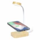 A wooden wireless charging stand with a flexible LED lamp and a phone charging on it.
