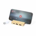 Smartphone on a wooden USB hub stand, playing a video, with a USB cable attached.