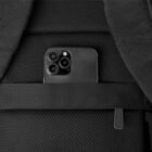 Black smartphone tucked into the pocket of a black textured backpack.
