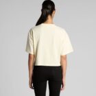 Person with long dark hair in a ponytail wears a cream t-shirt and black pants, back view.