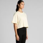 Woman wearing a loose cream crop top and black jeans, standing against a plain background.