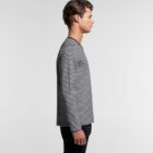 Man in black and white striped long-sleeve shirt standing in profile against a plain background.