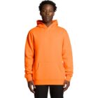 A person wearing a bright orange hoodie and black pants, standing against a white background.