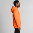 Man in an orange hoodie standing sideways against a plain, light gray background.