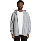 Man wearing a gray zip-up hoodie over a white T-shirt, standing against a white background.