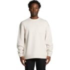 Man wearing a plain off-white sweatshirt with a chest pocket, standing against a white background.